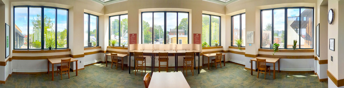 Floor layout - stretched from a panoramic setting - showing large windows and seating arrangements with six tables and eight chairs.