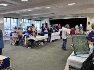 Organizations in search of volunteers set up booth-like-table displays while attendees navigate around the floor.