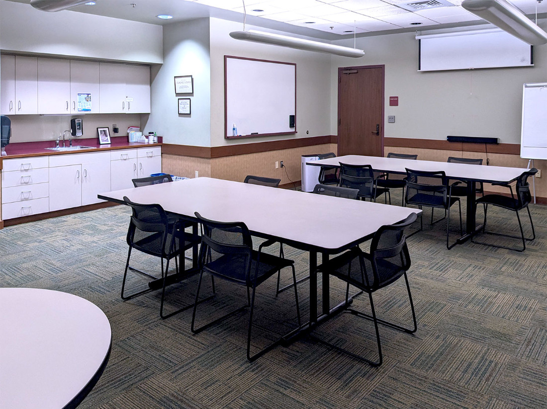 Looking towards the far-left of the room from the back-right. The kitchenette can be seen, as well as a whiteboard.