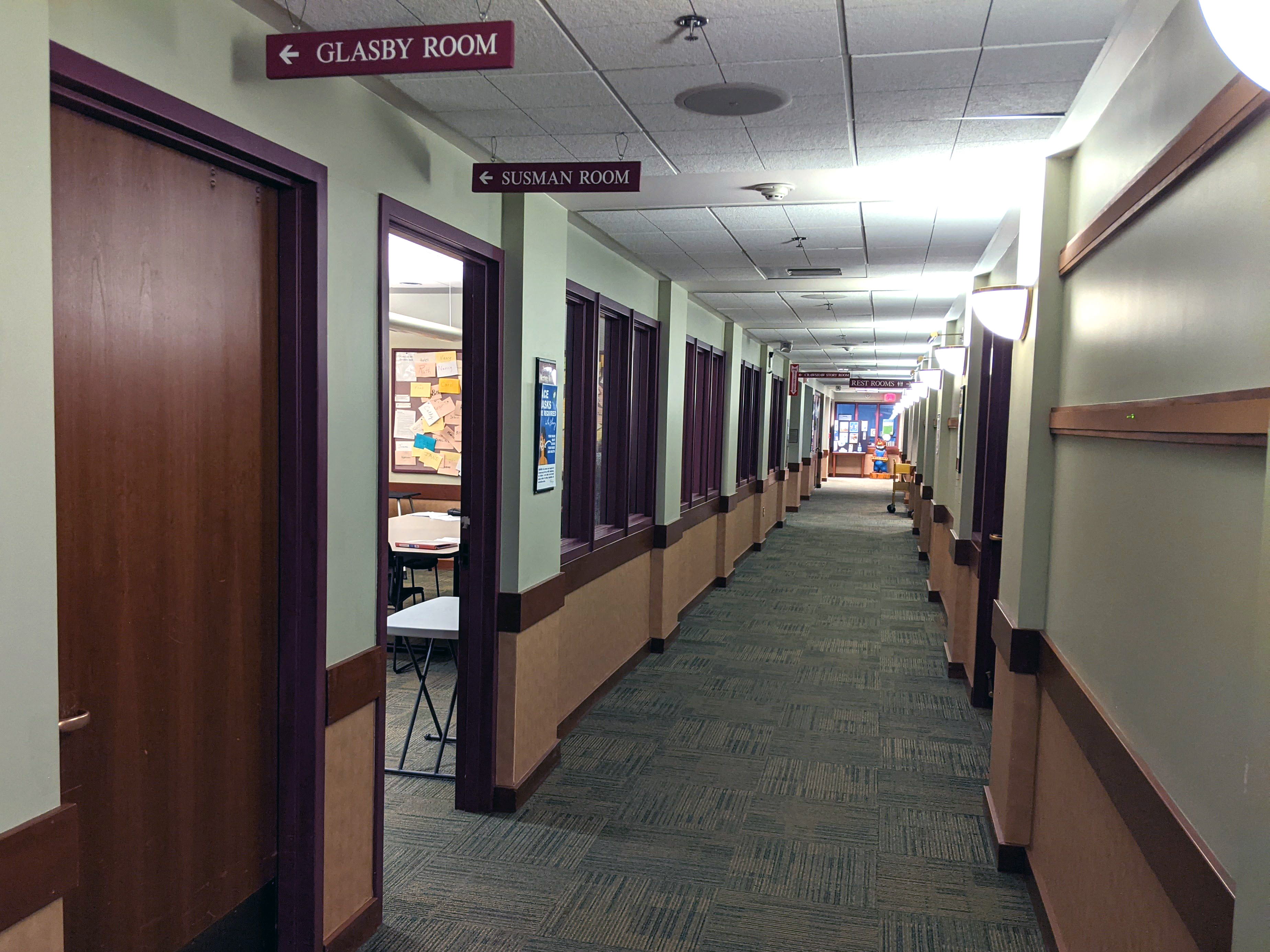 Long hallway with a doorway sign pointing to the Glasby Room entrance.