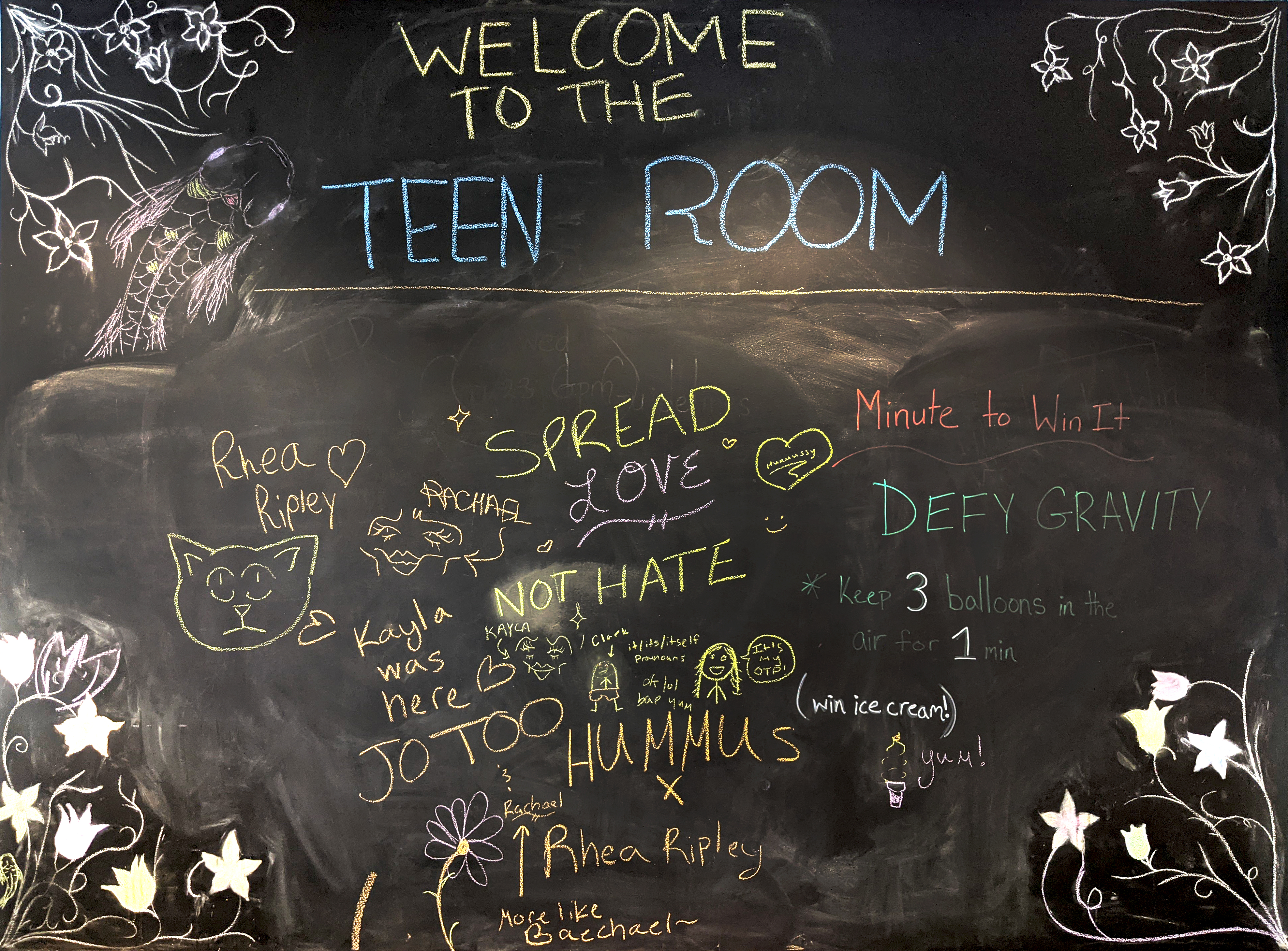 Announcement chalkboard with fancy artwork and random writings by staff and patrons alike.