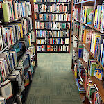 Thumbnail: Full shelves of books looking down an aisle towards yet another shelf full of books at the end.