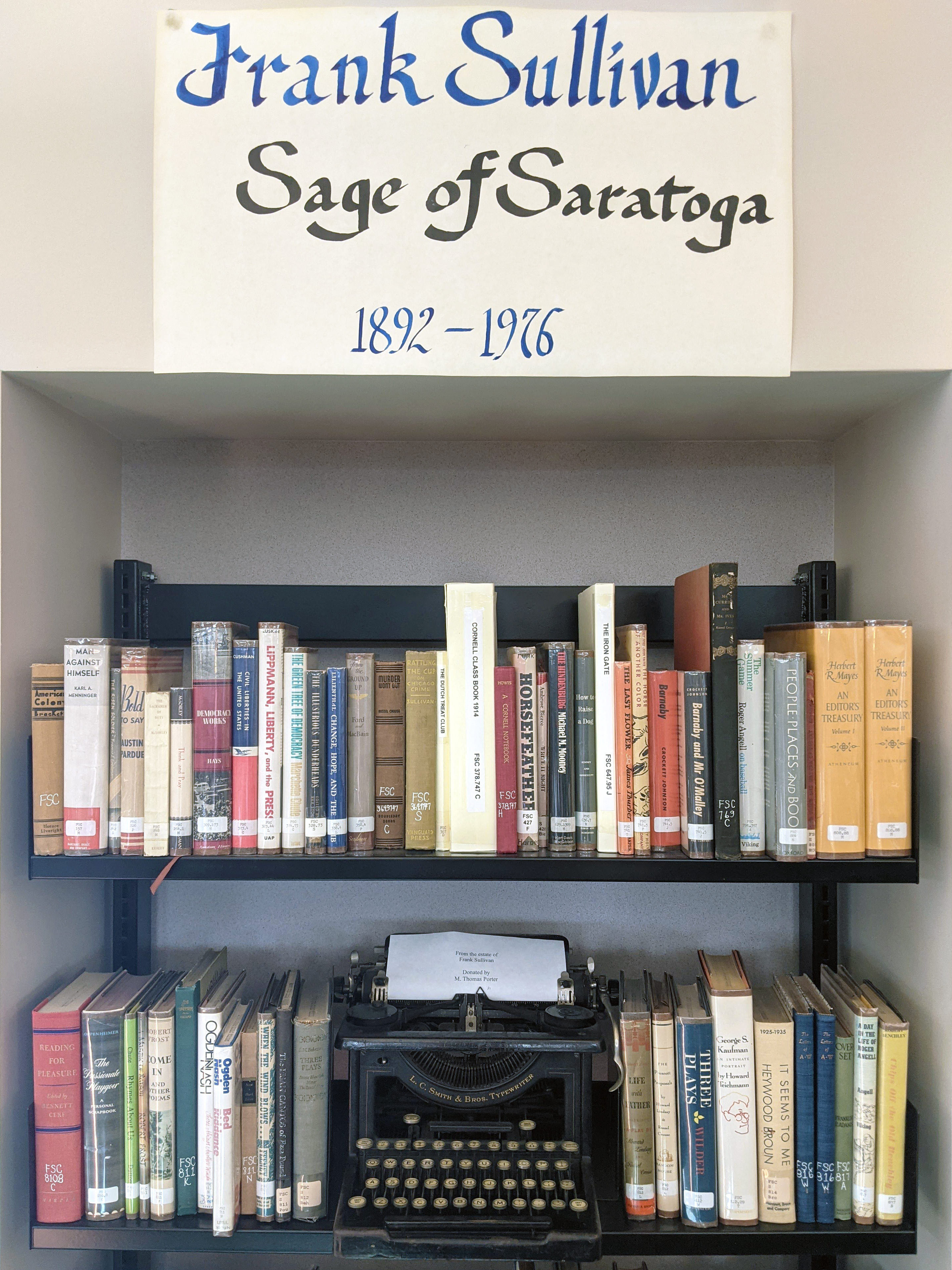Calligraphically written sign on paper, attached to a wall to designate a collection referencing material on “Frank Sullivan, Sage of Saratoga (1892-1976)”.
