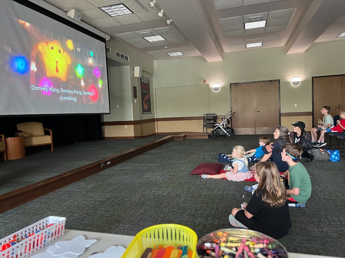 library patrons watch a movie in the community room