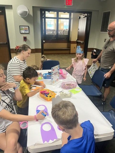 families create crafts at a table at the library