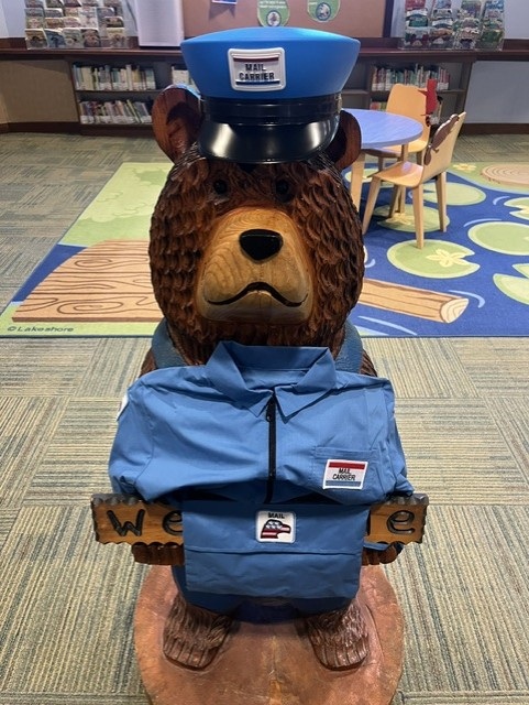 wooden bear dressed in a letter carrier costume