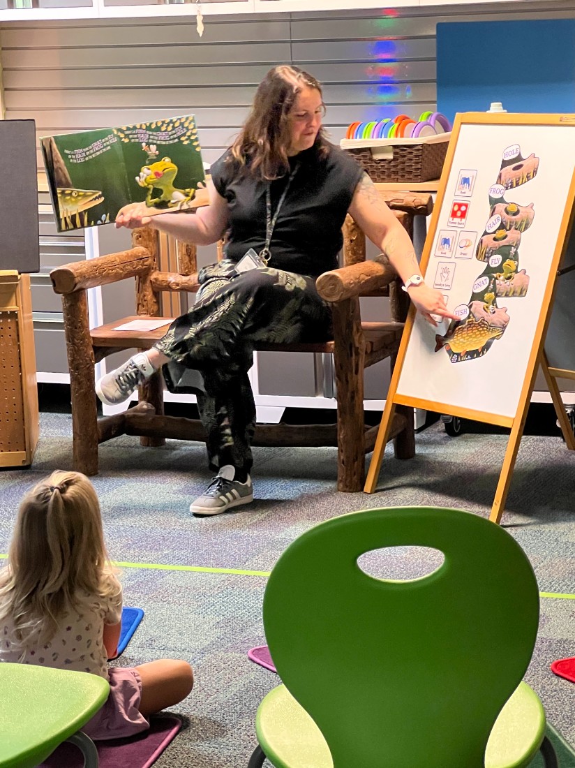 A librarian points at a flannel board during story time