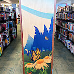 Thumbnail: An image of a butterfly landing on flowers with a forest backdrop decorates the end of a shelving unit.