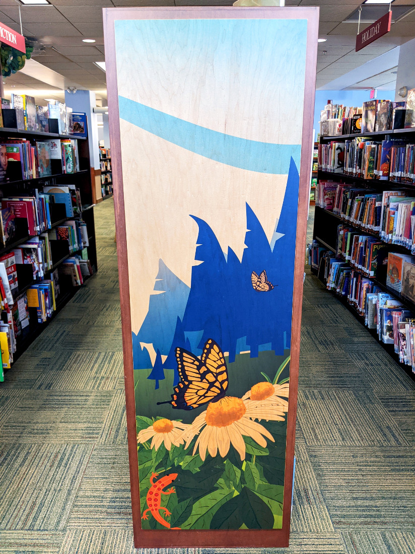 An image of a butterfly landing on flowers with a forest backdrop decorates the end of a shelving unit.