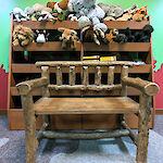 Thumbnail: A large wooden timber chair sits in front of a wooden shelving unit, with stuffed animals loaded throughout.