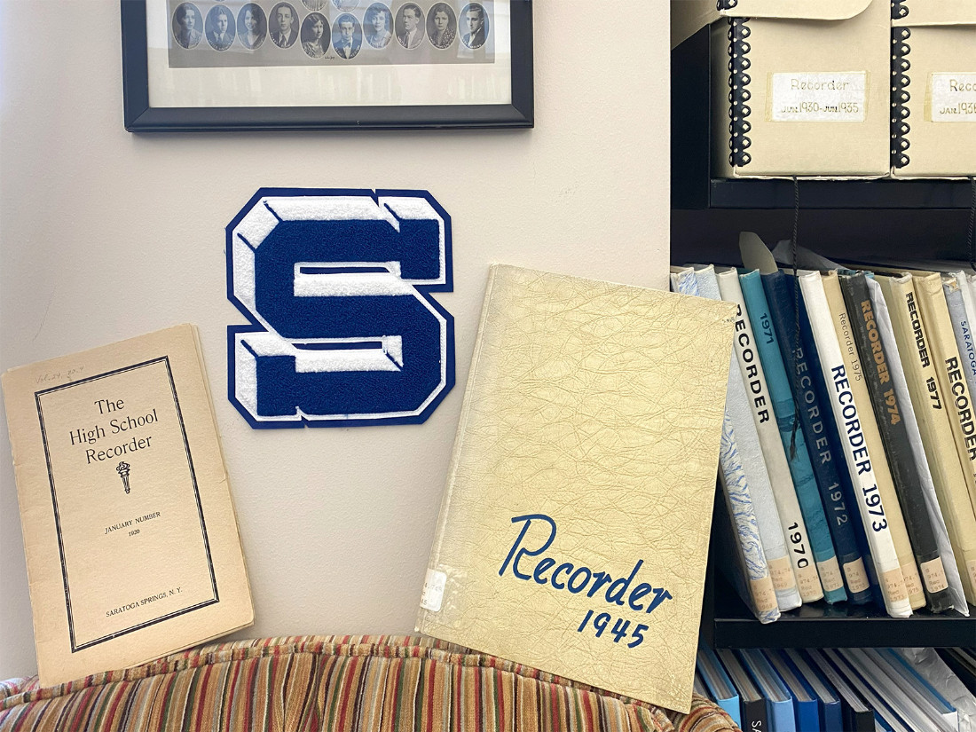 Saratoga Springs Senior High School’s Varsity Patch on the wall, between two examples of school yearbooks, titled “Recorder.”