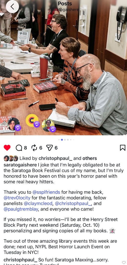 Three horror authors sit at a table signing books for festival attendees. Several copies of their books are visible on the table, along with pens, water bottles, and a Saratoga Book Festival sign.