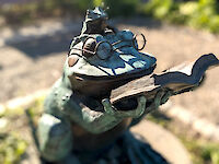 A sculpture of a large from reading a story from a book to a smaller frog that is sitting atop its head.