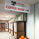 Thumbnail: A “Coffee Shop” sign hangs in front of an awning to doors, with orange celebratory balloons to grab attention.