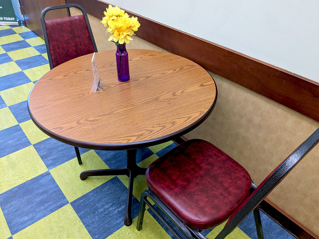 Two red, leather-cushioned seats surround a small circular table with a floral centerpiece.