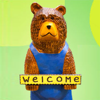 Henry the Bear, a children’s area mascot, holding his “Welcome” sign.