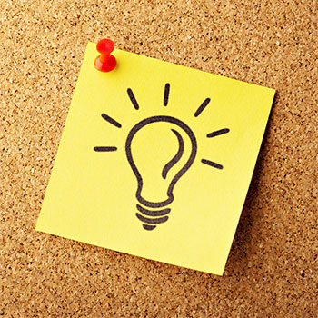 A lightbulb drawn with marker on a post-it note, pinned to a corkboard.
