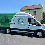 Thumbnail: A panel van, decorated with the library’s colors of green and white showcasing a two-tone photo depicting the library all in green on the back half and the library logo in green on white on the front.